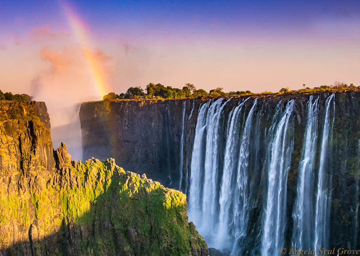 Victoria Falls Smoke That Thunders: Rainbow over Victoria Falls at sunrise.
